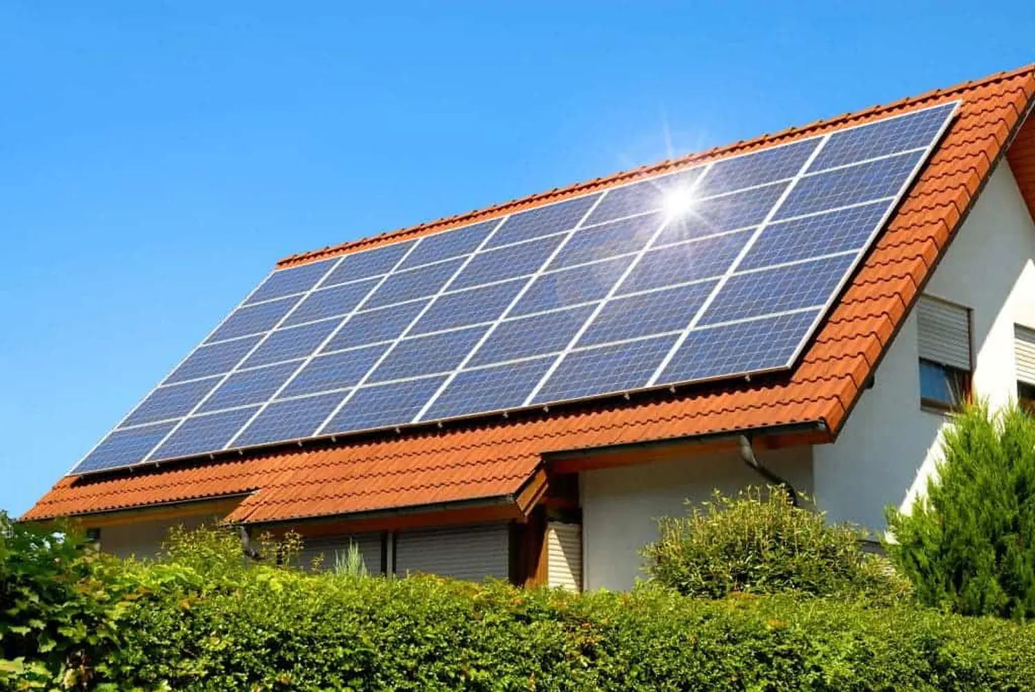 Ein Mann reinigt ein Solarpanel mit einem Besen auf einem Dach